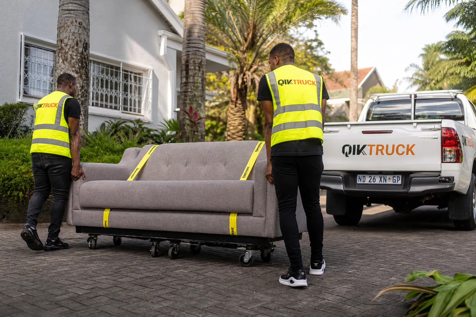 QikTruck crew rolling a sofa on a furniture trolley in a Durban suburb